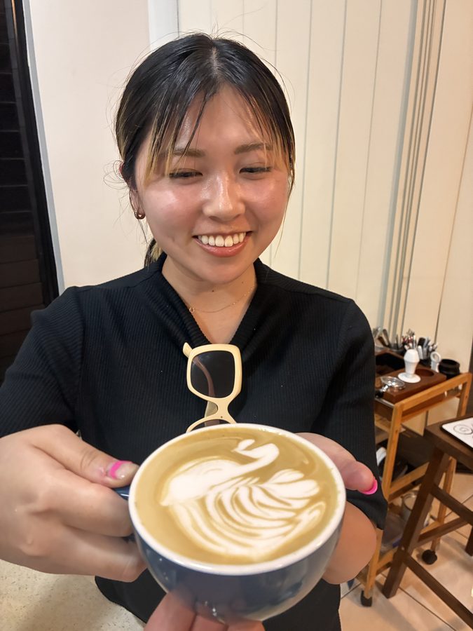 Student holding up their latte art coffee
